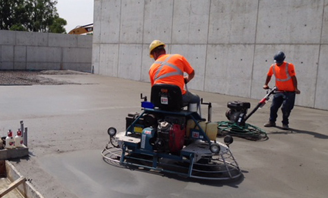 Workers smoothing concrete floor